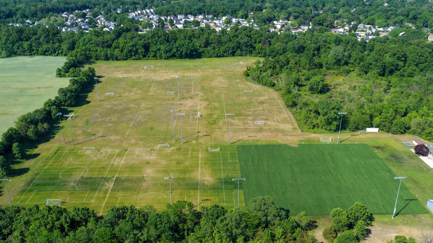 Wide aerial view of an athletic field complex and surrounding neighborhood