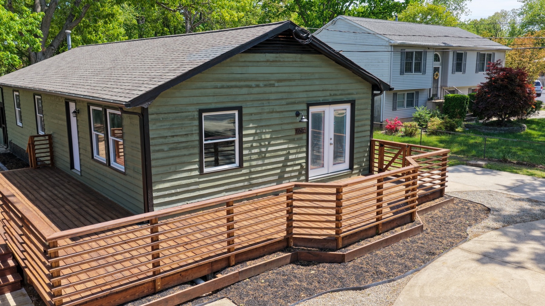 Aerial view of a house with a newly built wraparound deck during an exterior remodel