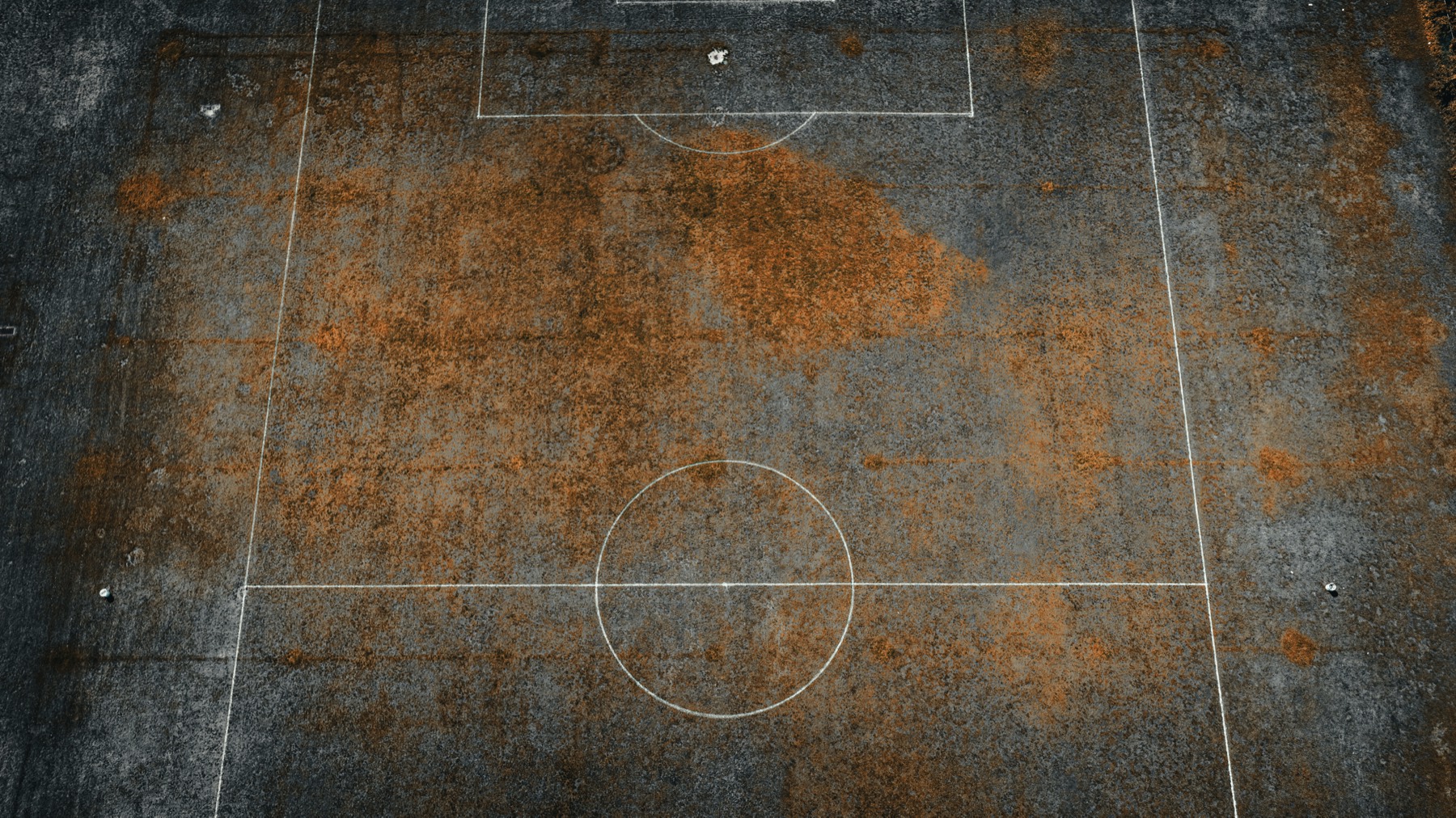 Close aerial view of a worn soccer field surface with faded field markings